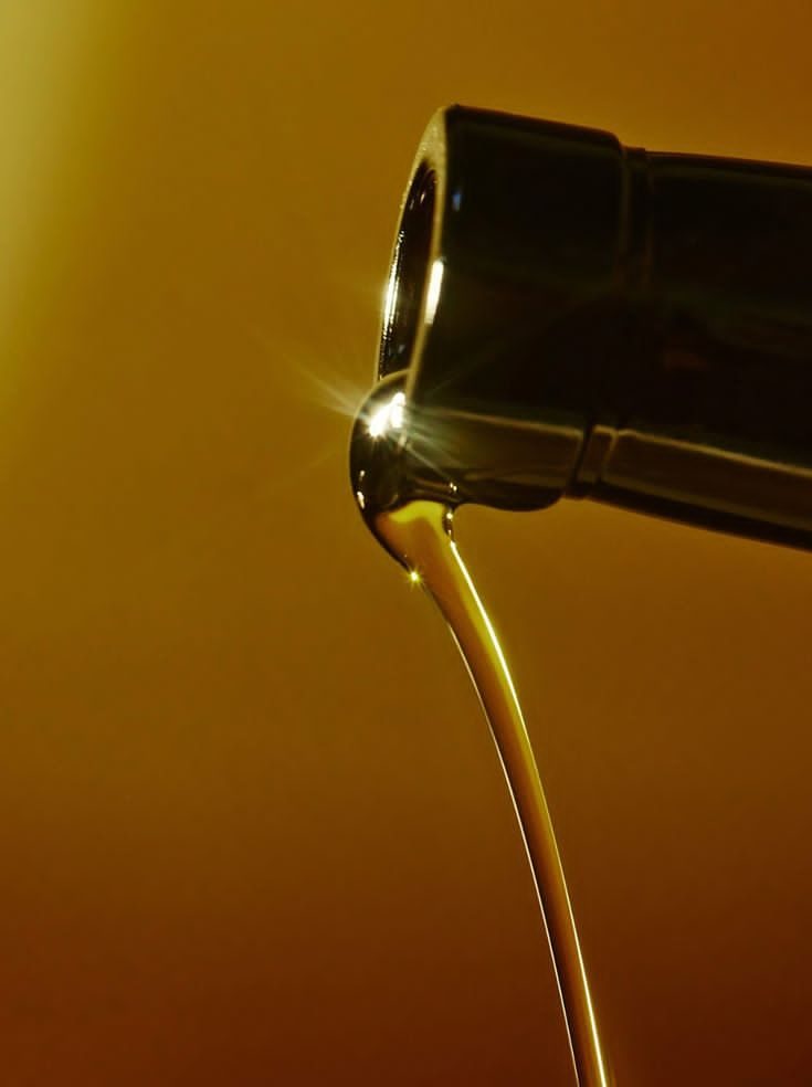 Filet doré s'écoulant d'une bouteille à contre-jour